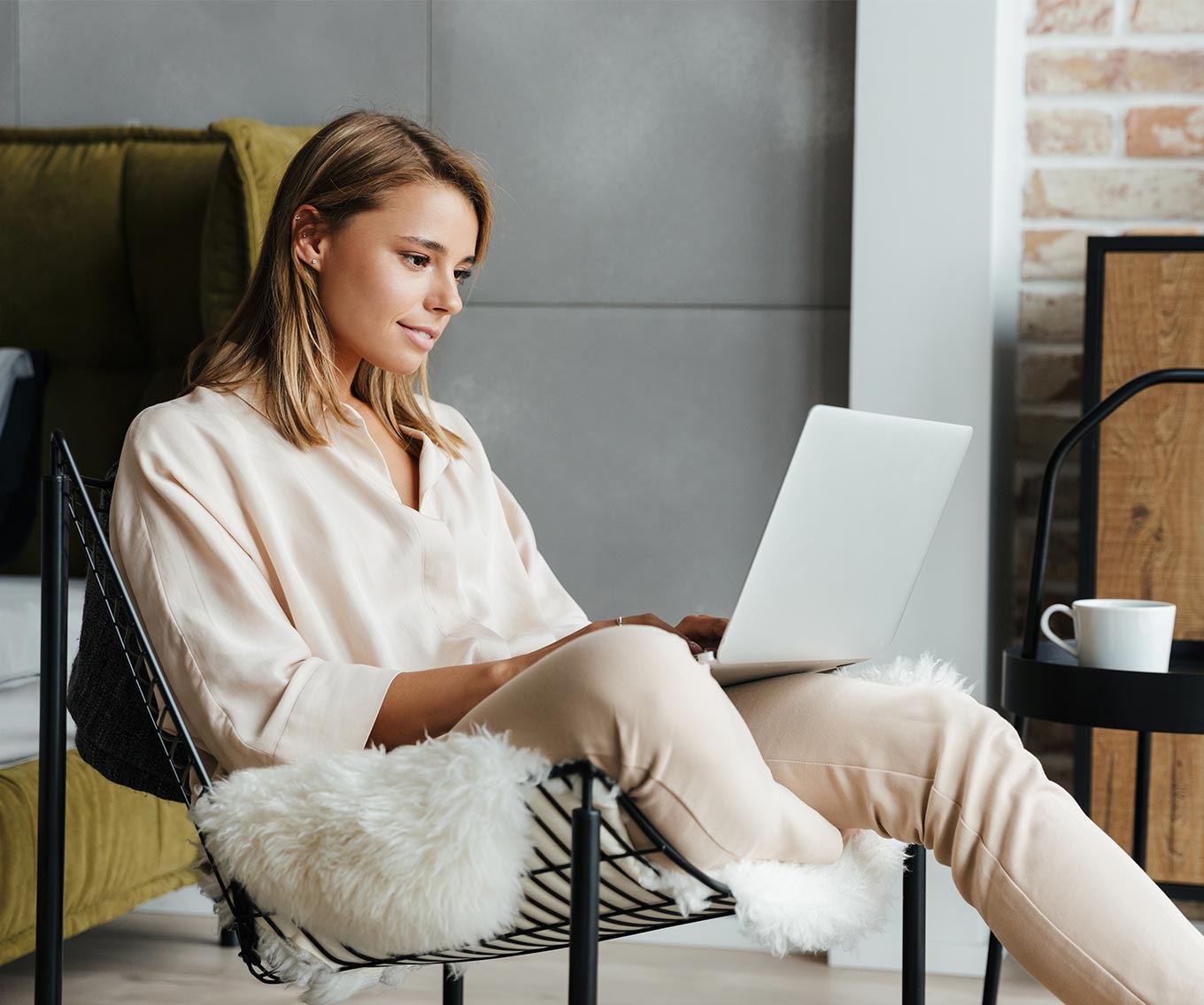 Woman sitting in chair at laptop researches assumable mortgage loans.