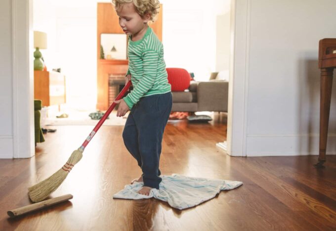 Child playing with broom in family home