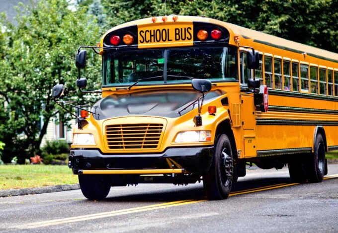 Yellow school bus for local school district driving through neighborhood.
